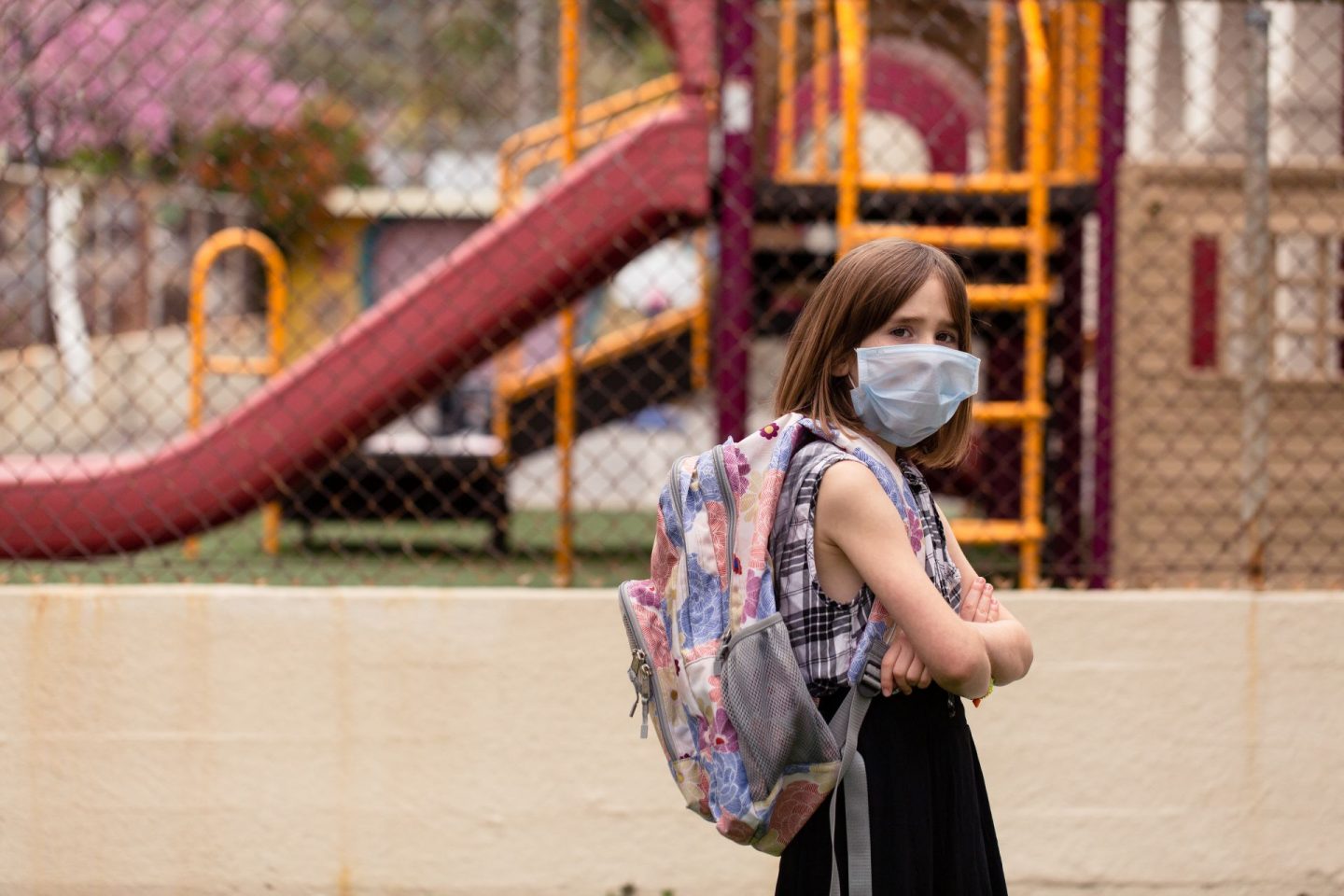 Schoolgirl with facemask outside her school, preparing children for the return to school