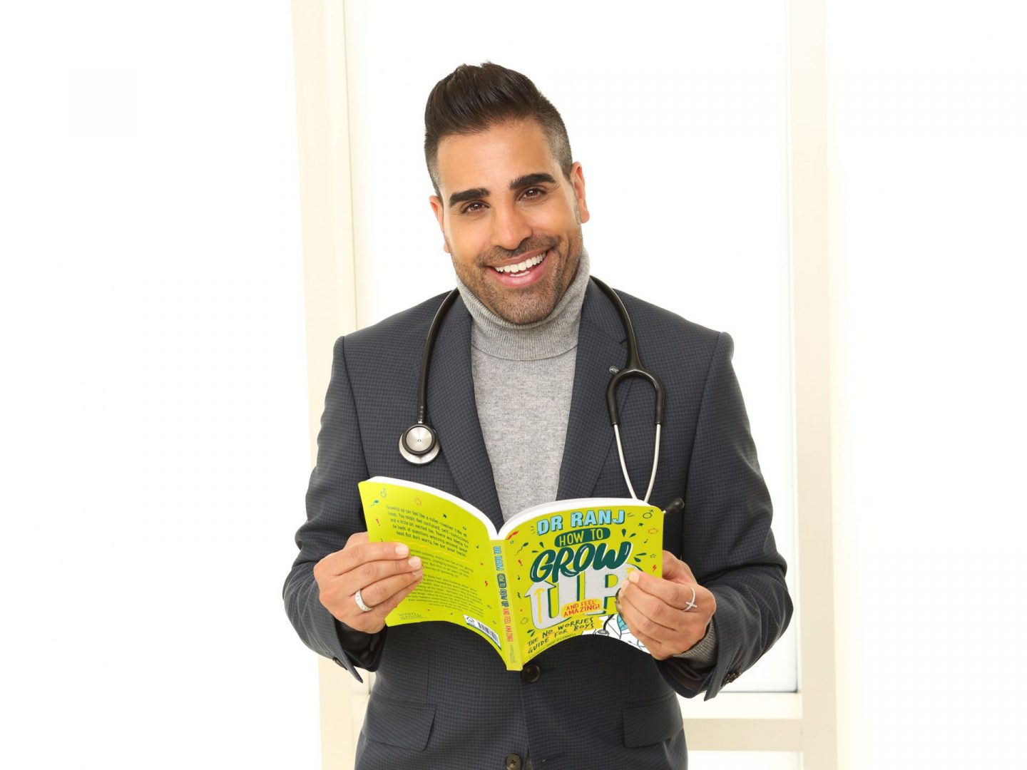 Dr Ranj Singh holding copy of How to Grow Up and Feel Amazing
